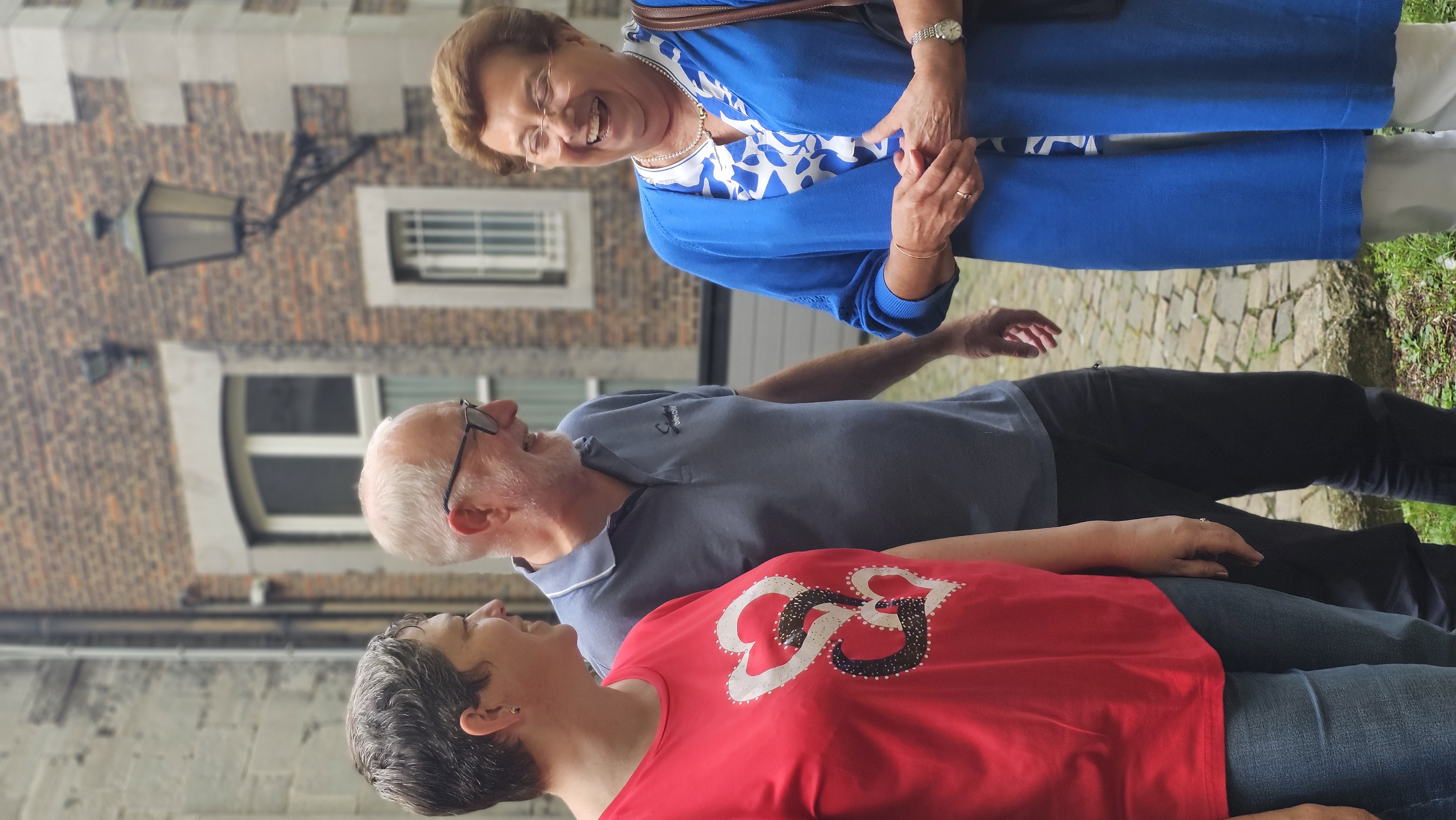 Marie-Annick Danze, Michel Uyttendaele et Anne-Marie Meunier partagent un éclat de rire dans une cour pavée
